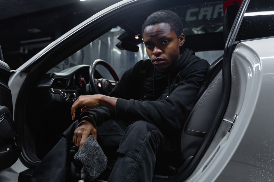 Young man cleaning car interior with cloth, emphasizing car care and maintenance.
