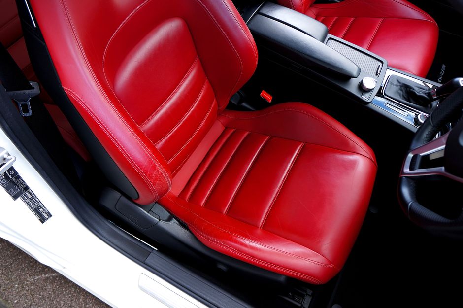 A detailed view of a red leather car seat in a modern car's interior, showcasing luxury and style.